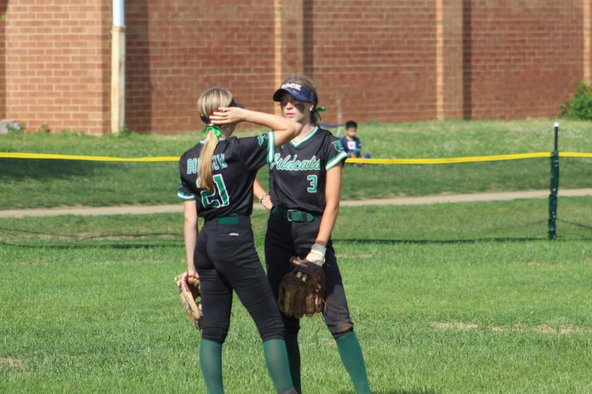 Sophomore Addie Strbak converses with sophomore Elizabeth Borrisow in the outfield during their fundraiser game against Springbrook High School on May 2. The players all wore green ribbons in their hair throughout the game to symbolize mental health awareness. (Seyun Park)