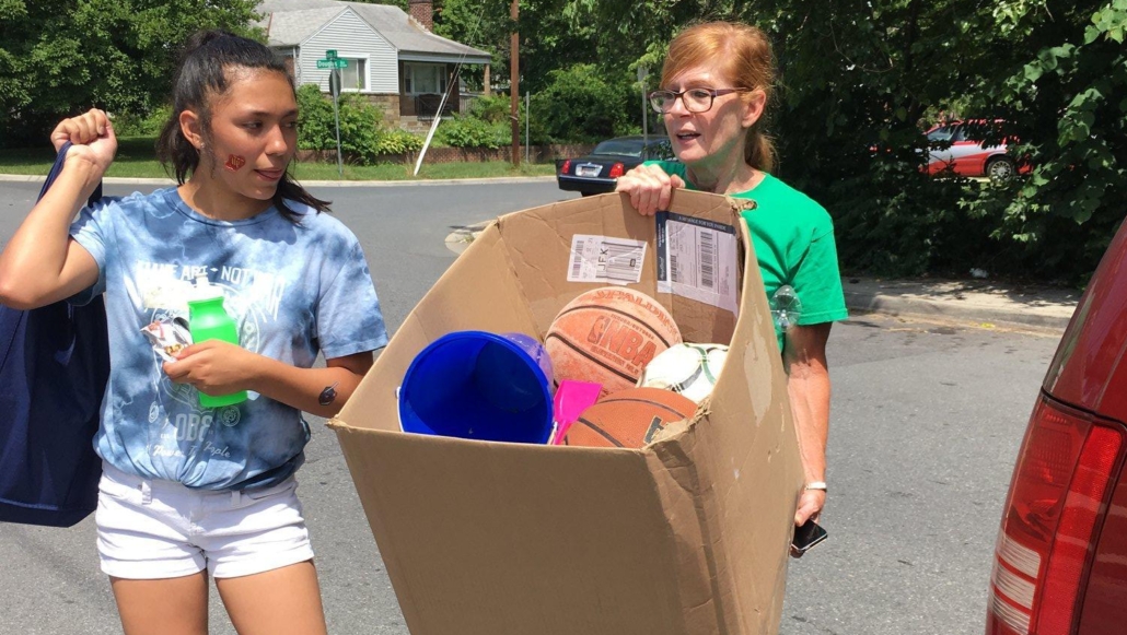 Two women donate their old basketballs and soccer balls to their local elementary school. They did some summer cleaning in their shed and found lots of sports equipment that they no longer needed to take up space. (Courtesy KindWorks)