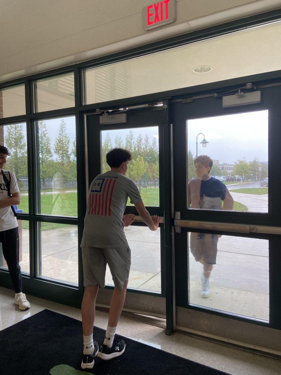 Sophomore Jonah Wishnoff opens the door for sophomore Ryan Aleman near the weight room. Students are strongly discouraged from letting anyone in and should instead walk by and allow the security system to do its job.