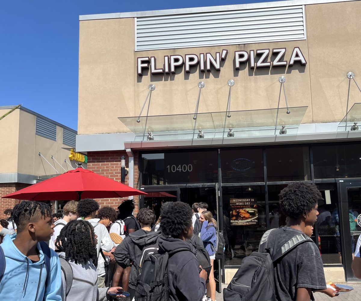 A line of students stretches far past the door at Flippin' Pizza, an almost daily occurrence during the school year. Inside, employees work hard to quickly serve their customers.