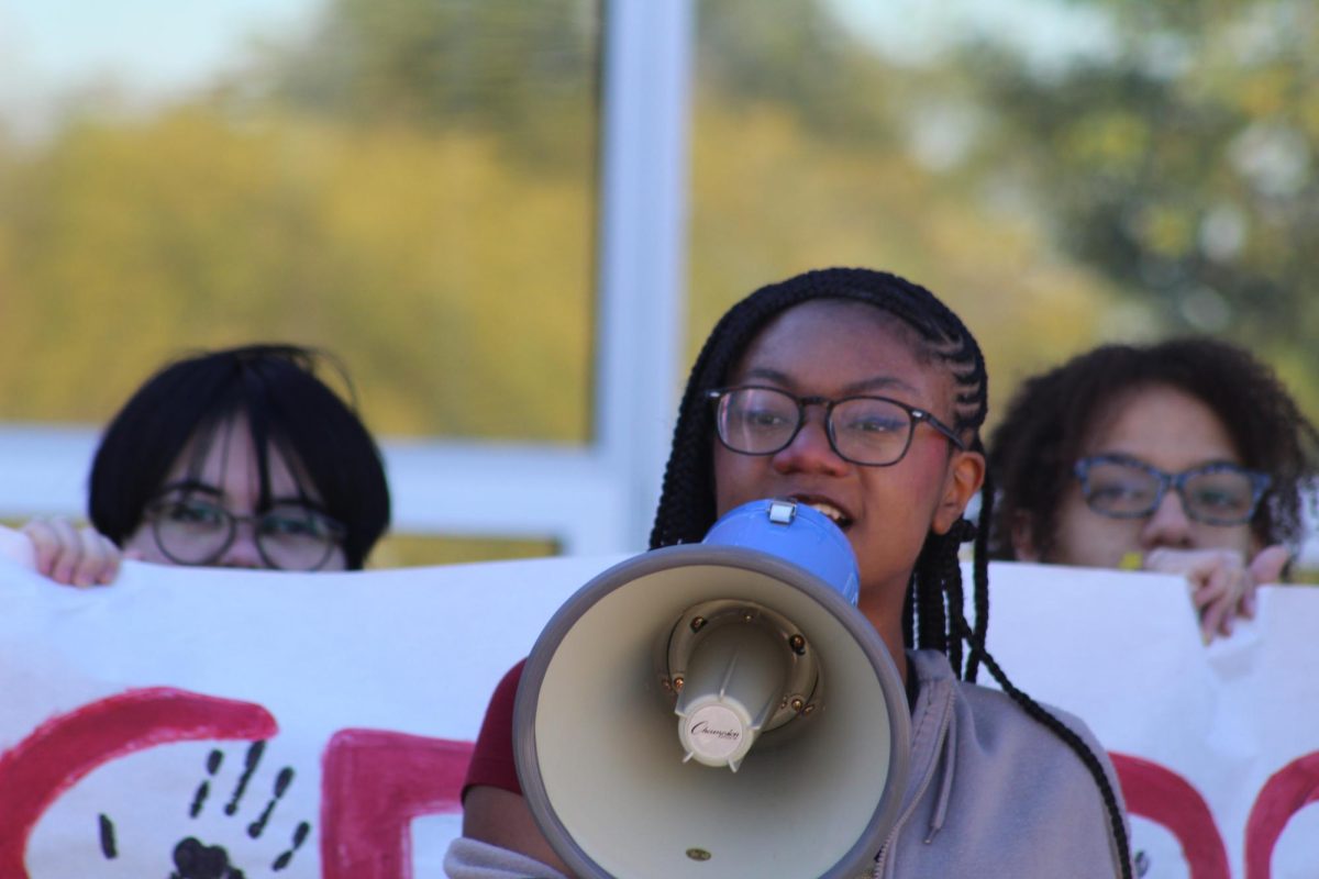 Senior Michelle Lett speaks through a megaphone about an incident at Wootton last spring in which a student printed 1,000 copies of paper with a racial slur on it. "This is applicable; this is not only just Wootton, it's countywide," Lett said.