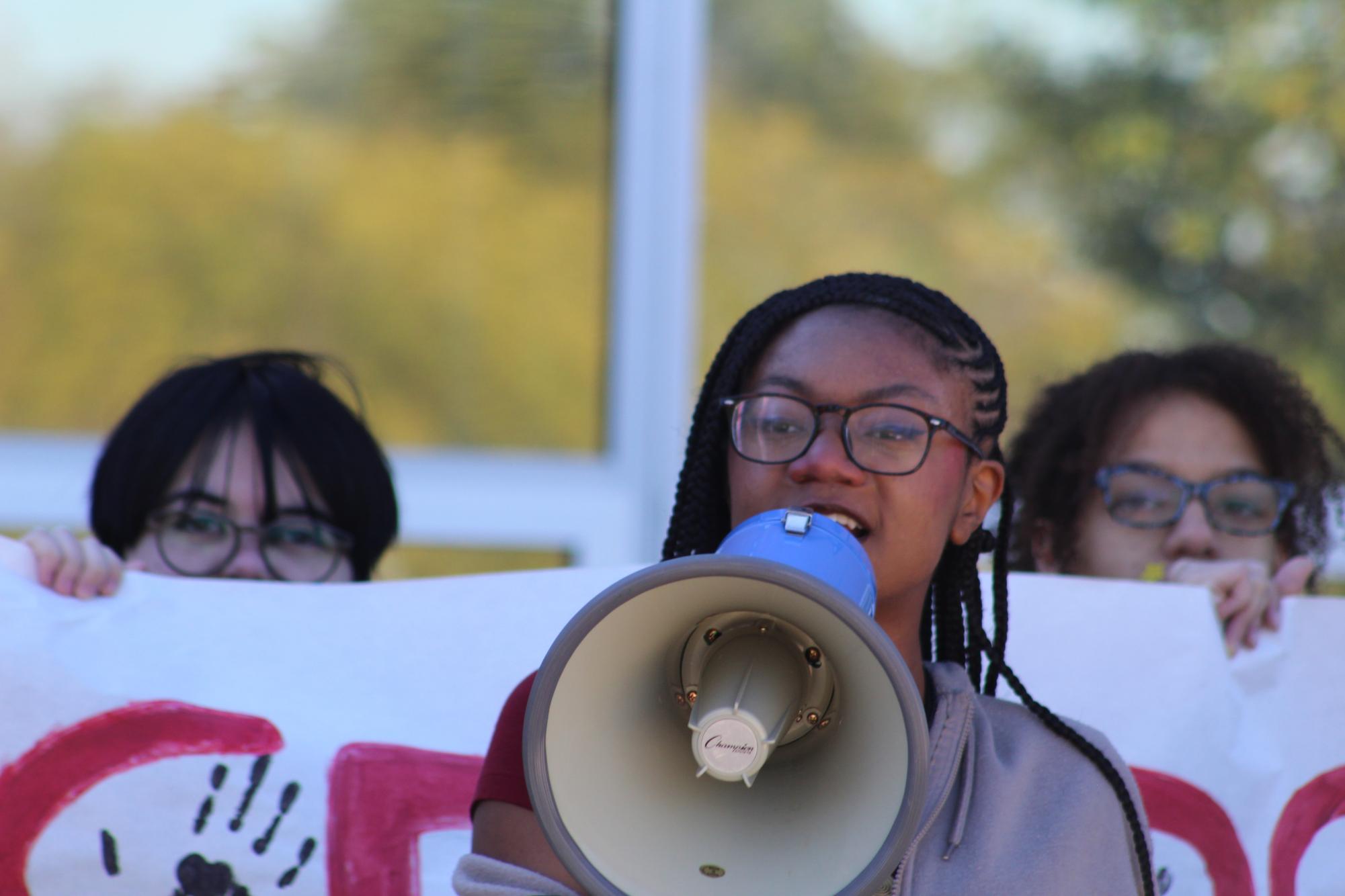 Senior Michelle Lett speaks through a megaphone about an incident at Wootton last spring in which a student printed 1,000 copies of paper with a racial slur on it. "This is applicable; this is not only just Wootton, it's countywide," Lett said.