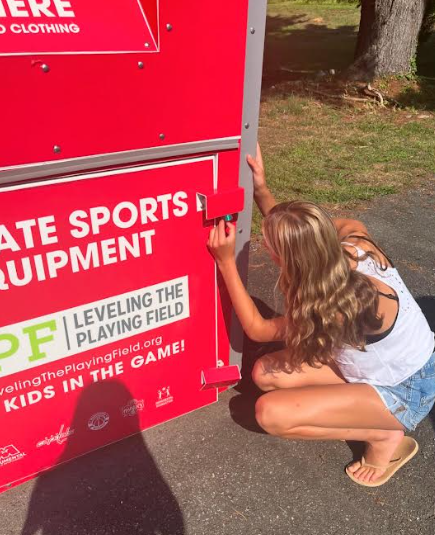 Junior club treasurer Lily Bienfang unlocks the equipment collection bin. As of April 2024, the WJ LPF club became the bin ambassador for the Falls Road bin.