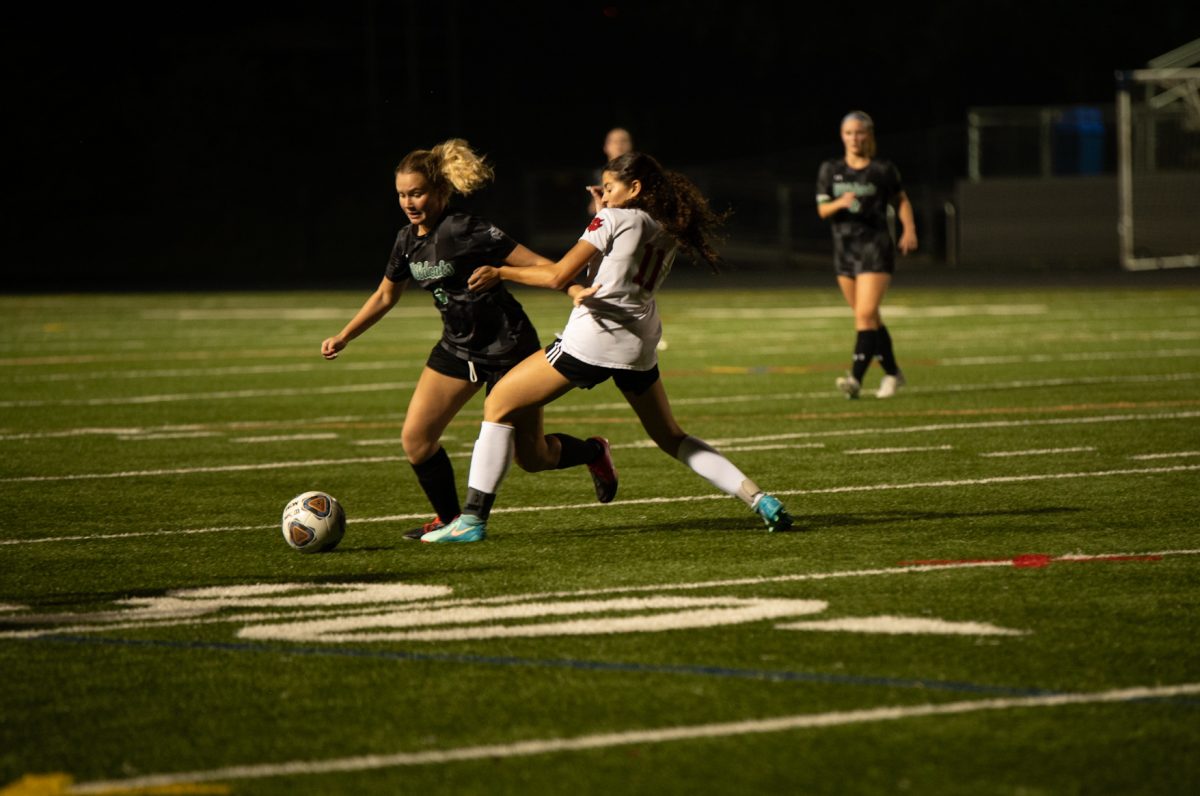 Senior Ginger Fishberg defends the ball against an opposing player during a varsity girls' soccer game against Blair. Despite her obvious athleticism, as well as that of other varsity athletes, she is still required to take a full year of Physical Education to earn the credit. (Courtesy Lifetouch)