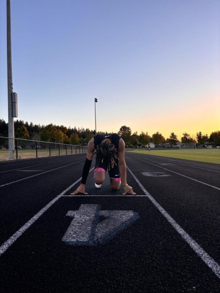 Junior Alessandro Marenco gets into the runner's starting stance as the sun sets over the track. Marenco was one of the four boy sprinters who earned a spot in Nike Nationals in Eugene, Oregon last year. (Courtesy Ariel Stone)