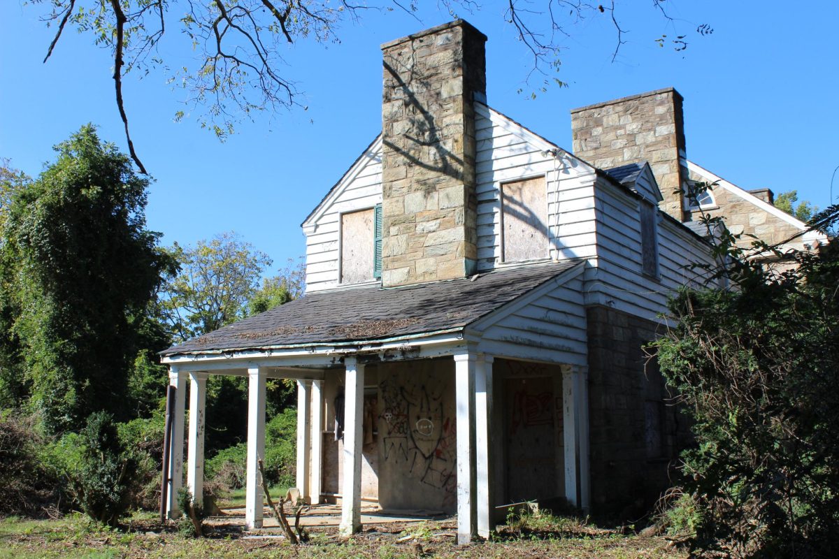 The derelict Davis Mansion, built in 1926, sits a short distance from the WJ school building. After 40 years of abandonment, the house's exterior has become covered in graffiti and overgrown foliage, creating a foreboding appearance.