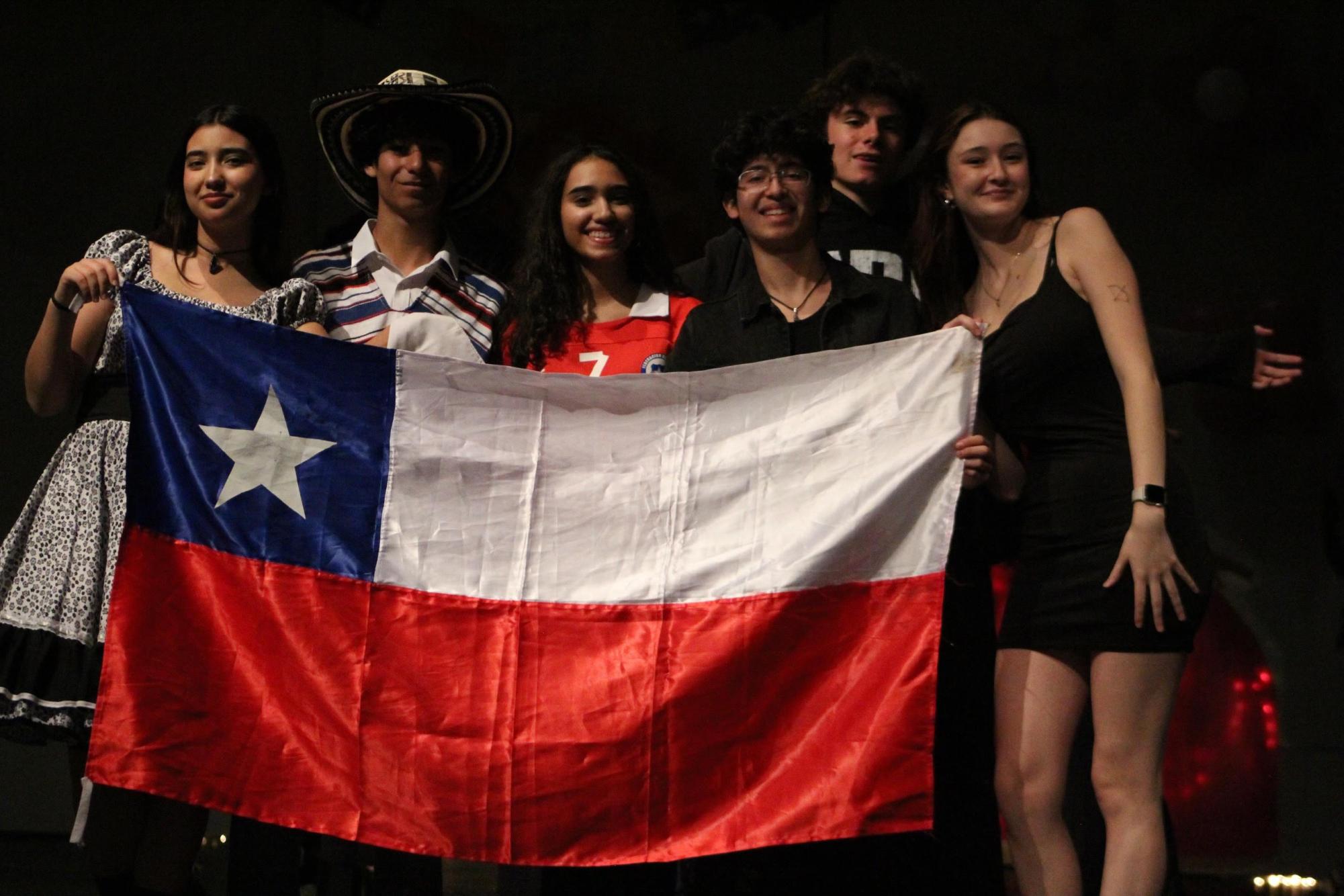 From left: Senior Emilia Rizik, sophomore Maximiliano Utreras, freshman Catalina Maurin, junior Ignacio Utreras, freshman Bautista García and senior Elisa Karich proudly display the Chilean flag. This group of students is just one of several in the Hispanic and Latin American assembly that put various aspects of their identity on display at the event.