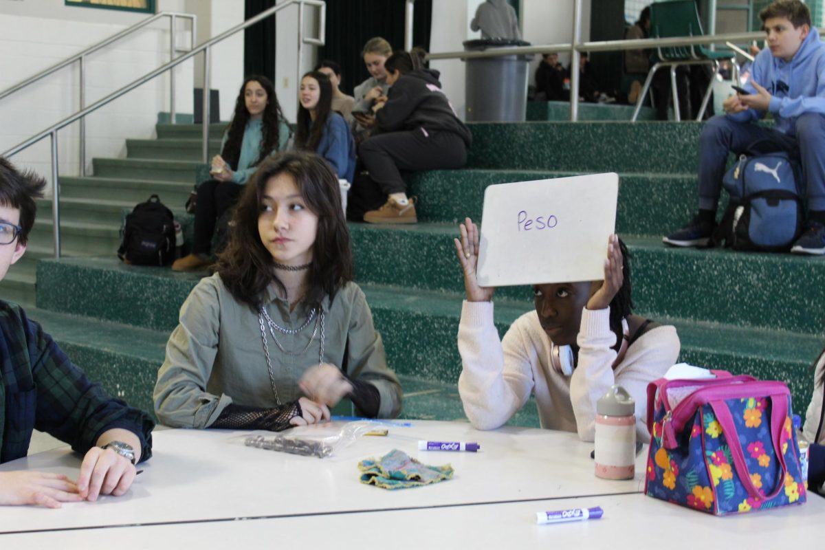 A student holds up her answer to a trivia question as her teammates look to the projector screen for the answer. Most of the questions were random, but the tiebreakers focused, appropriately, on the heart.