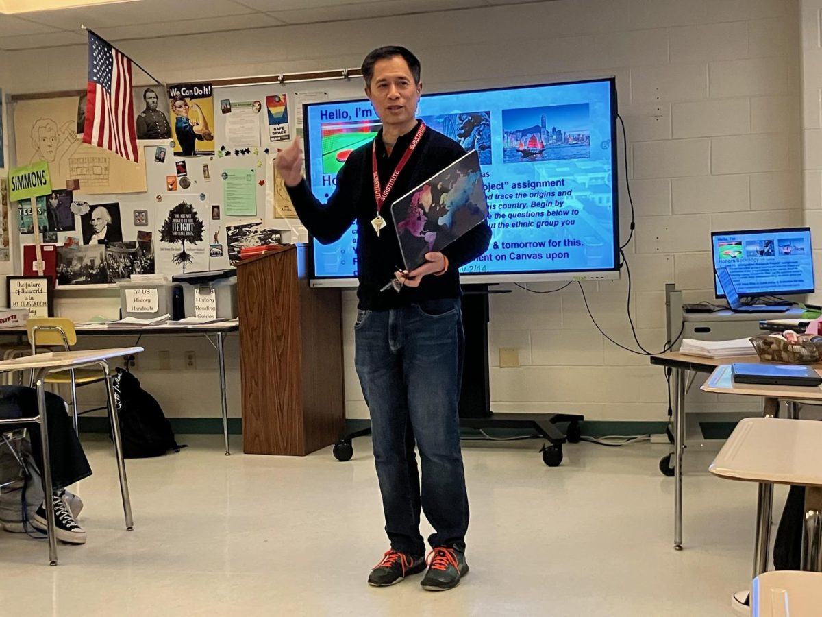 Substitute teacher Kenneth Ong introduces himself to an Honors Sociology class using his self-made slideshow. He developed the slides as a method to combat unpreparedness, a frequent issue for some substitutes due to a lack of resources.