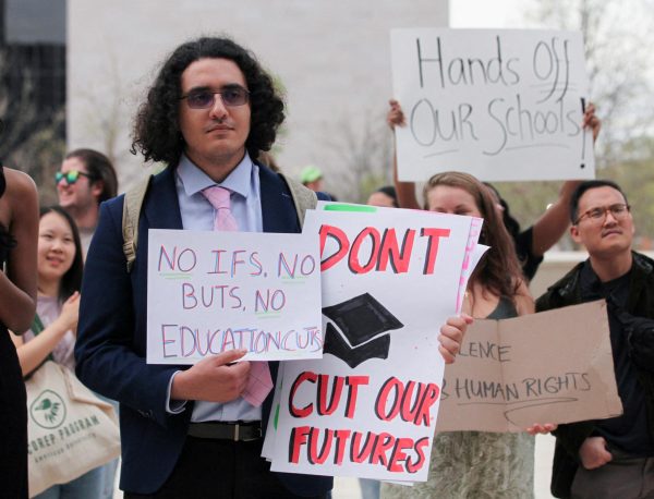 A demonstrator holds placards as students from Washington, DC universities protest U.S. President Donald Trump's dismantling of and funding cuts to the Department of Education, in Washington, U.S. April 4, 2025. REUTERS/Allison Bailey