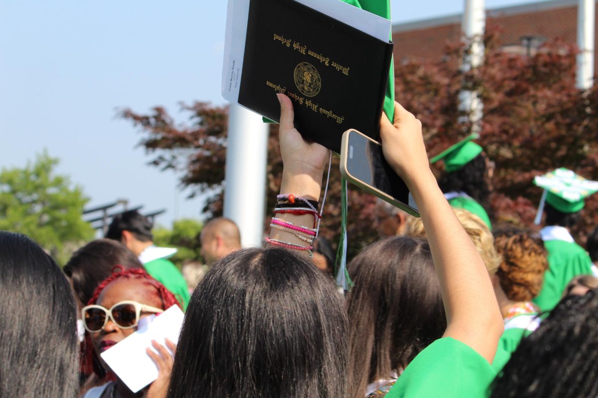 A senior holds her diploma in the air after the two-and-a-half-hour ceremony. This marks not only the end of a chapter, but the beginning of a new one after years of hard work and perseverance. 