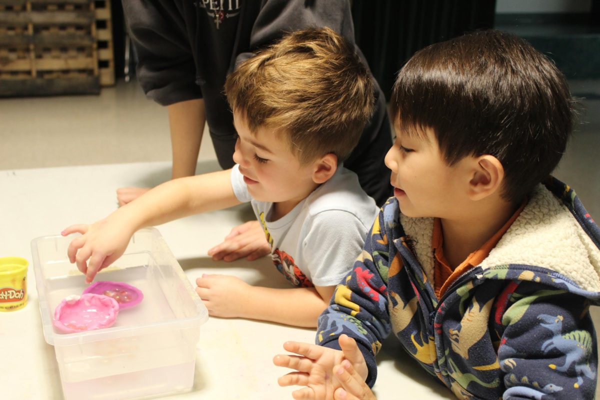 Zaeem and Chase admire the bright colors of the play-dough while trying to understand why one floats and the other doesn't. NSHS students placed marbles inside the boat shaped play-dough to show how objects can float while holding something.