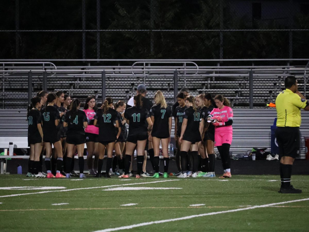 The WJ girls' soccer team huddles around Head Coach Neil Gottlieb, preparing to ramp up the team spirit during their pregame tradition of "Jump Around." The Cats trampled the Trojans on senior night, 4-1. 