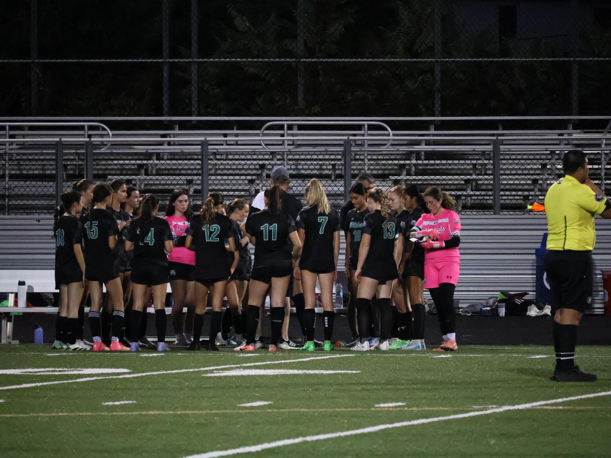 The WJ girls' soccer team huddles around Head Coach Neil Gottlieb, preparing to ramp up the team spirit during their pregame tradition of "Jump Around." The Cats trampled the Trojans on senior night, 4-1. 