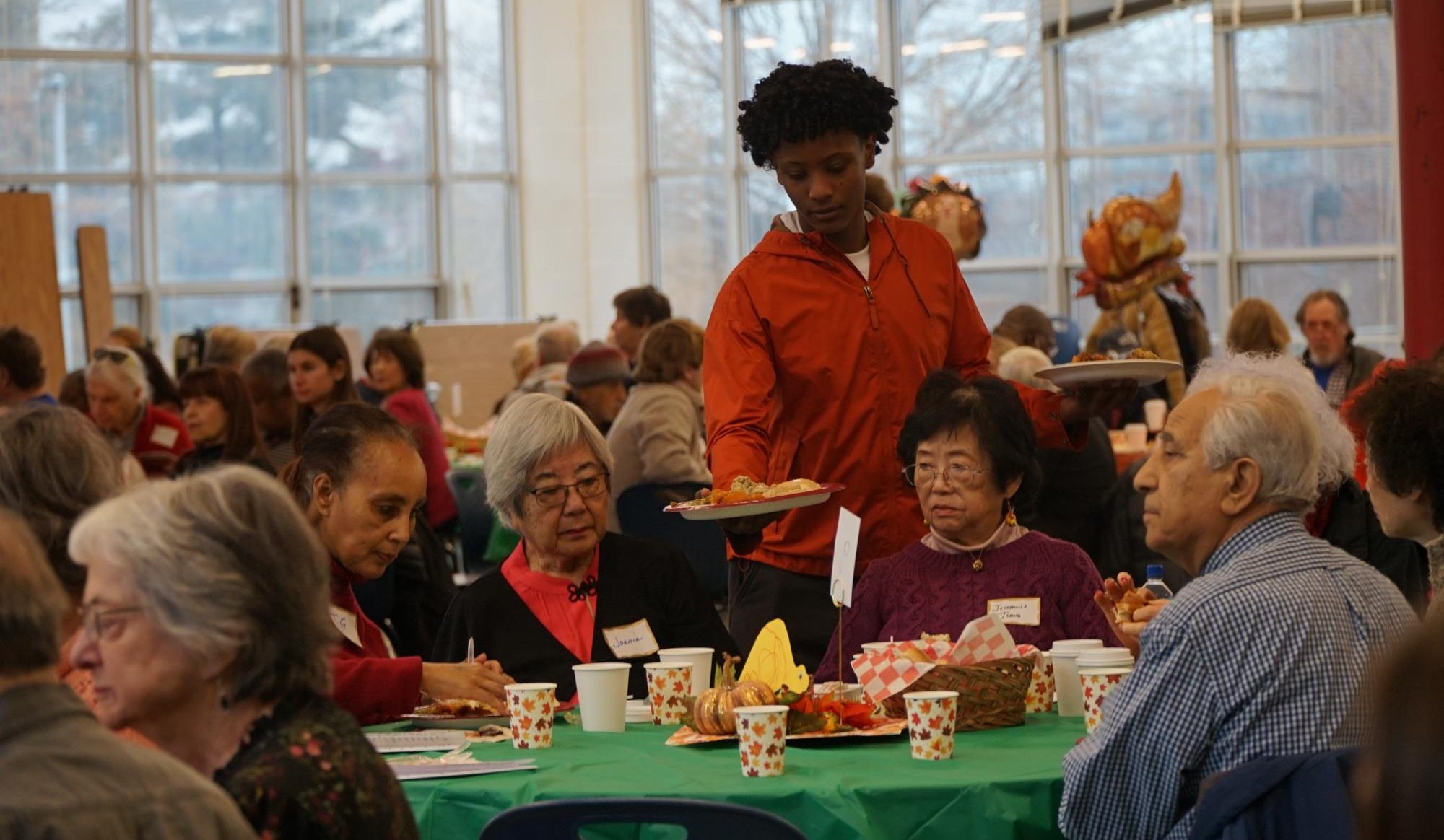 WJ student serves a Thanksgiving meal to senior citizen as they listen to the performances. "I love being a table host because I love listening to people's stories and listening to the older generation talk about their life experiences," senior Eden Chase said.
