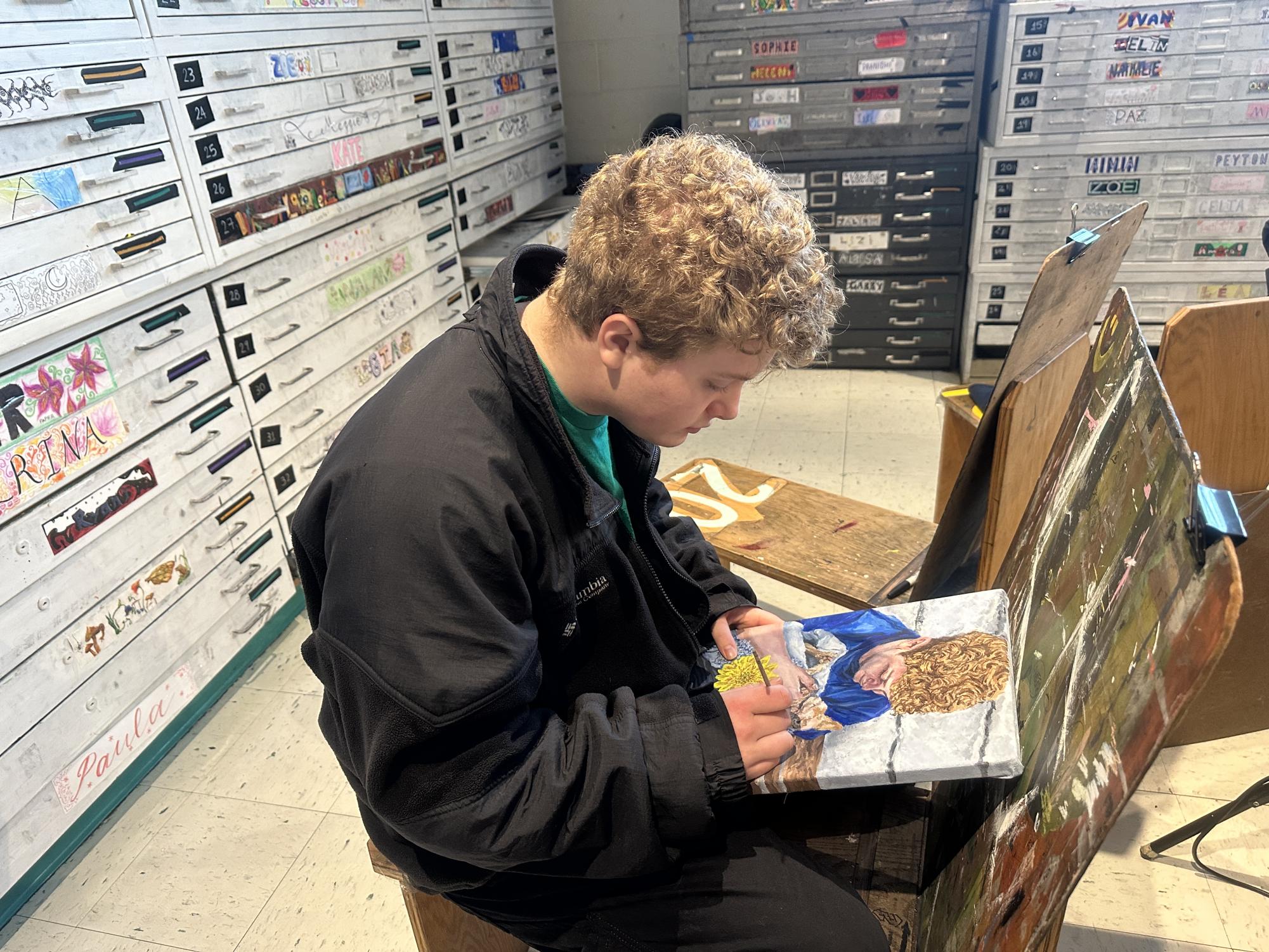 Senior Ashton Hyer works on one of the sustain investigation pieces of his cat and himself right before she passed away, using plants to represent important aspects of someone's life. "The blue ones are forget-me-nots, and the yellow ones are marigolds, and they represent remembrance and like the happy aspects. Because thinking about the happy aspects of a pet or a person's life is just as important as the sadness when it comes to grief," Hyer said.