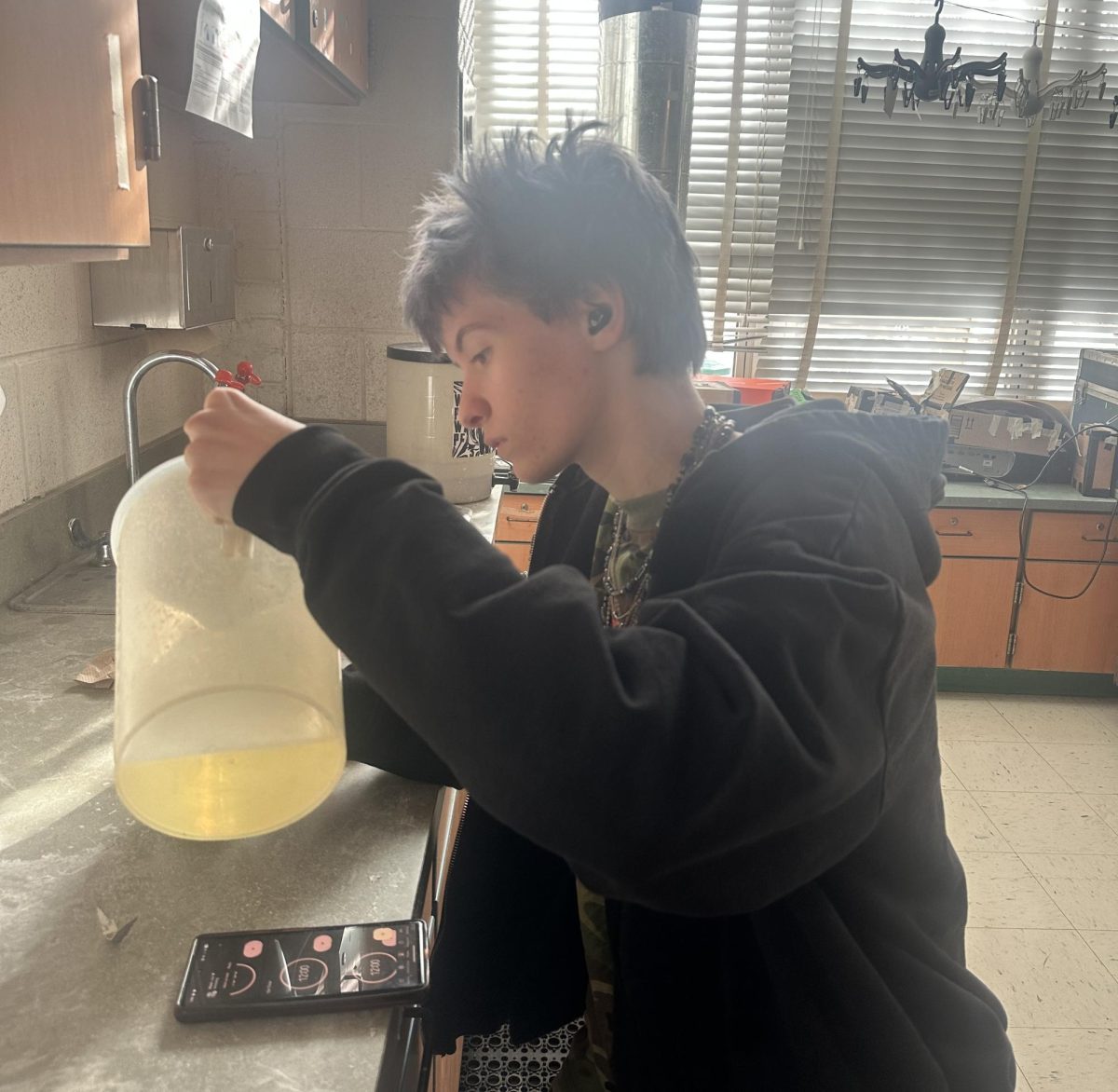 Senior Ryan Hemingsley starts the process of developing his rolls of film. He's pouring developer, a chemical that reduces the exposure and reveals the image into a tank where his rolls of film are reeled onto a spool, which ensures the chemical can access the entire surface of the film.