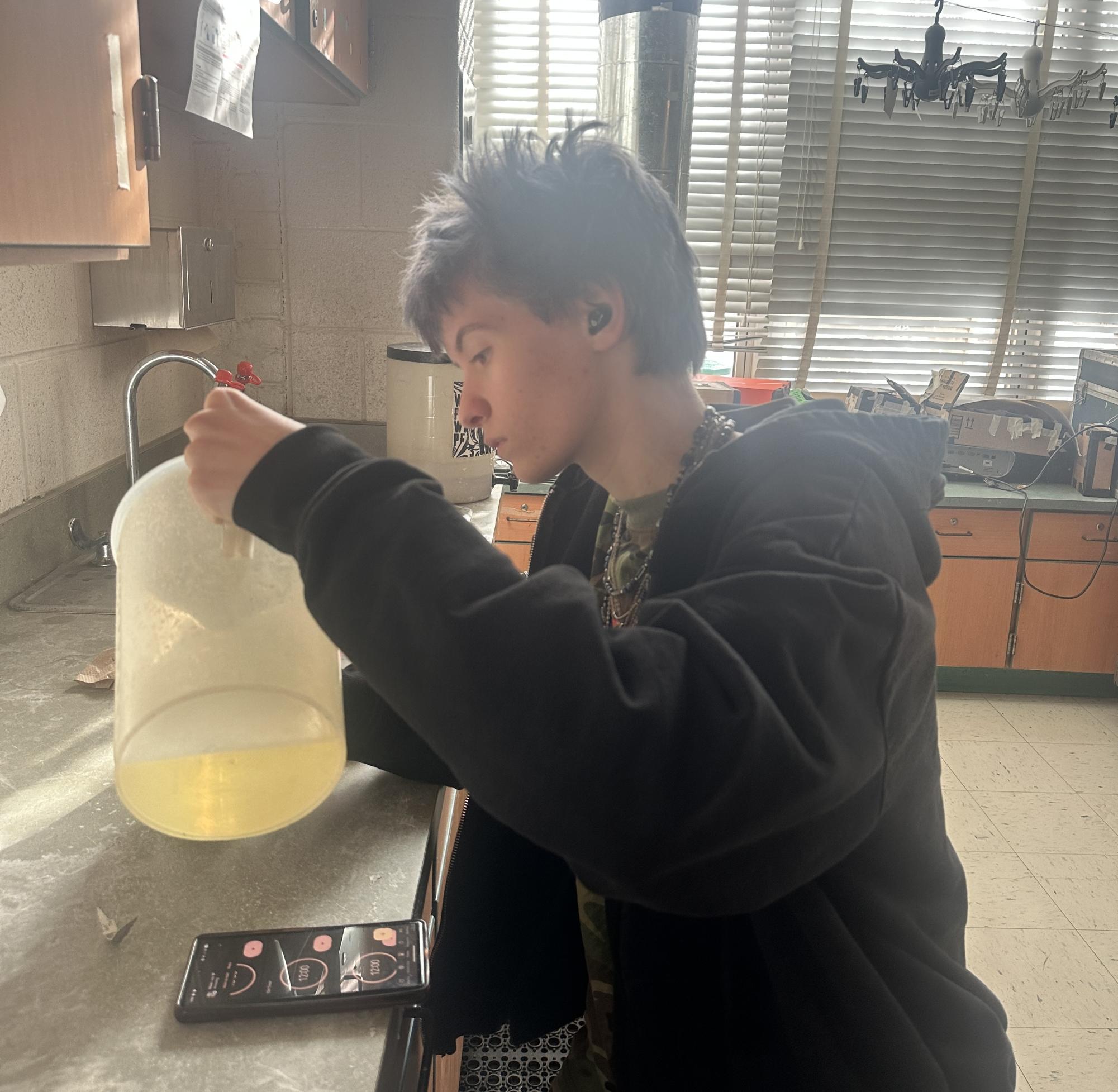 Senior Ryan Hemingsley starts the process of developing his rolls of film. He's pouring developer, a chemical that reduces the exposure and reveals the image into a tank where his rolls of film are reeled onto a spool, which ensures the chemical can access the entire surface of the film.