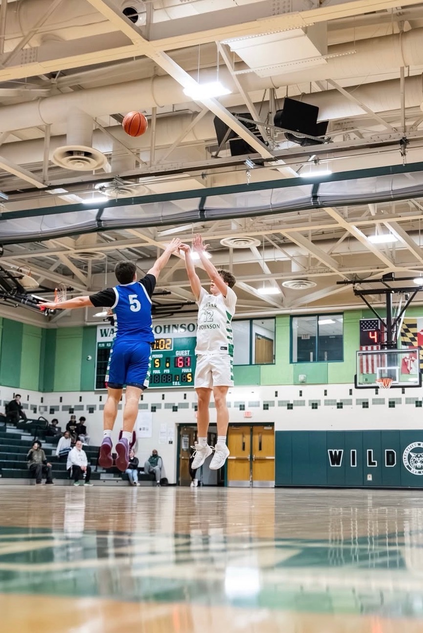 Junior guard Connor Luecking shoots a three-pointer in overtime during the final regular season matchup between the Churchill Bulldogs on Feb. 23. The Cats came back from a first-half deficit to win, giving the team some confidence heading into the playoffs.