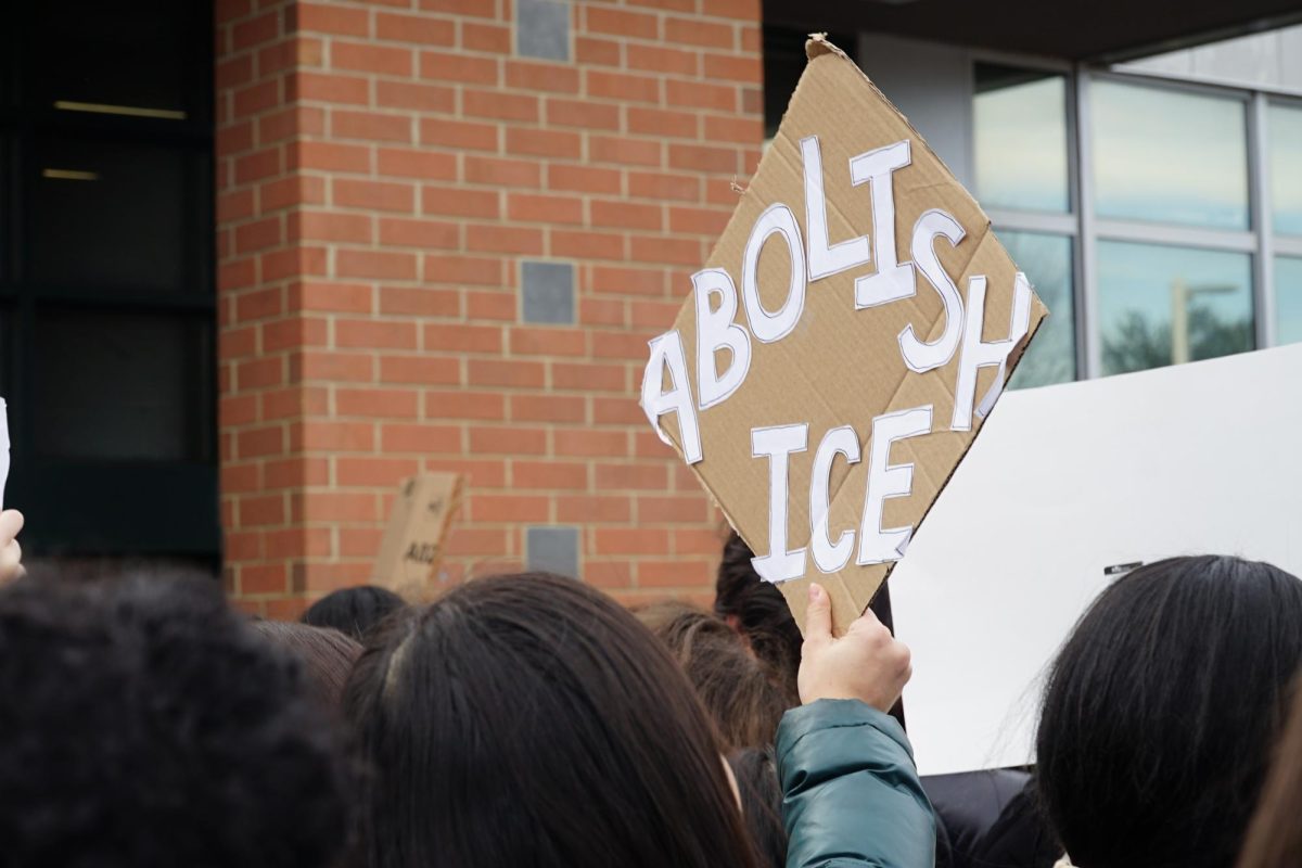 A student raises an "Abolish ICE" sign above the crowd during WJ's first walkout on Jan. 26. Slogans are easy to hold up; the real question is whether students are willing to stand behind them when consequences follow.
