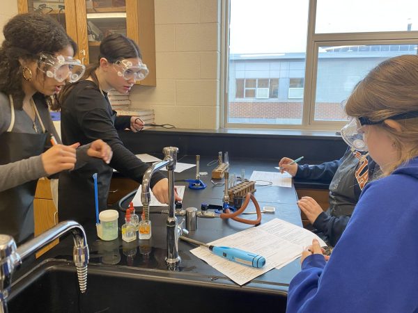 Chemistry students complete part of a lab in Honors Chemistry that requires them to heat copper over a bunsen burner. The new Astronomy with Physics course would allow students to avoid a full course of chemistry completely.
