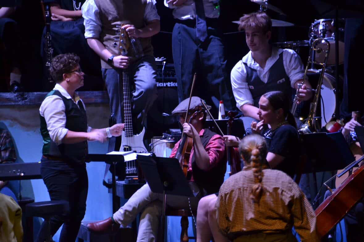 Music teacher Andrea Morris talks to senior trombonist Theo Hansen and senior violinist Alice Bradley before the show. Hansen and Bradley were two of the pit's many musical powerhouses who helped bring the music of Hadestown to life.
