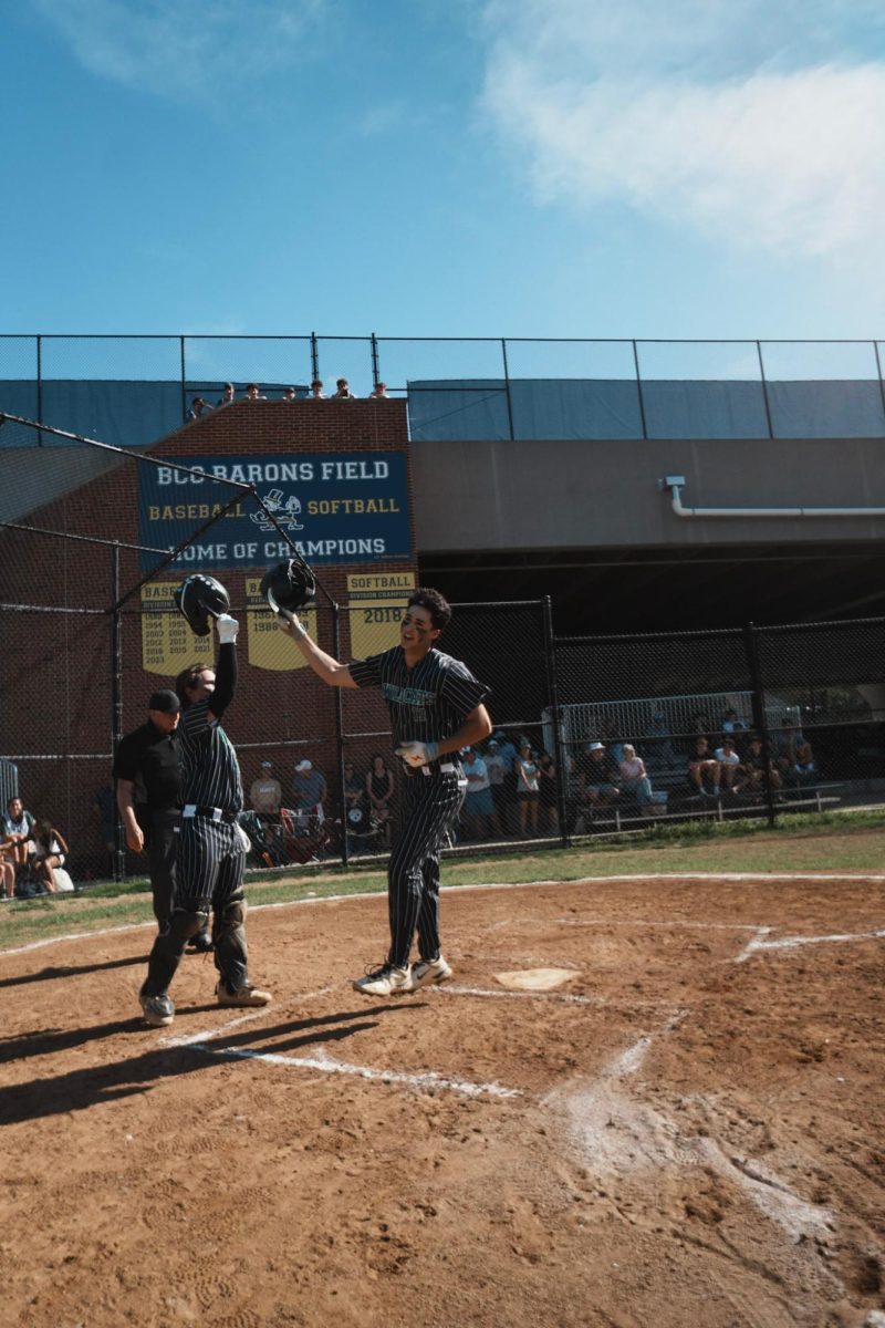 Seniors Ethan Pletter and Sam Weston touch helmets as Pletter gets home against B-CC. The Cats went on to beat the Barons 11-2. (courtesy Liam Snow)